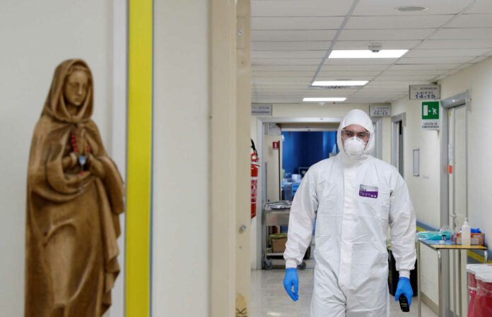 A medical worker in a protective suit walks in an aisle of the San Filippo Neri hospital in Rome